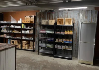 Butikshyllor i Klosterbiets butik fyllda med drycker från Bryggeri Viktoria och biodlingsprodukter.